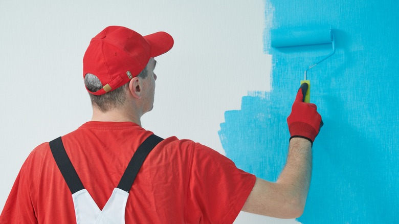 Man painting white wall blue