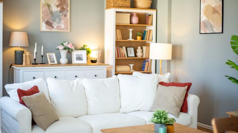 A cozy living room with open bookshelves, a white sofa, and a cabinet