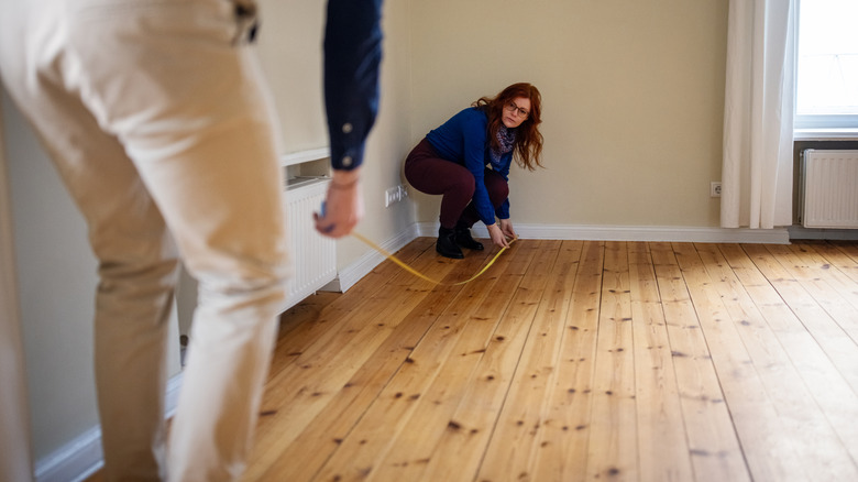 Two people measuring a room