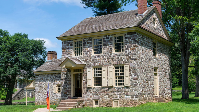 Old, two story stone house with pitched roof and dual chimneys.