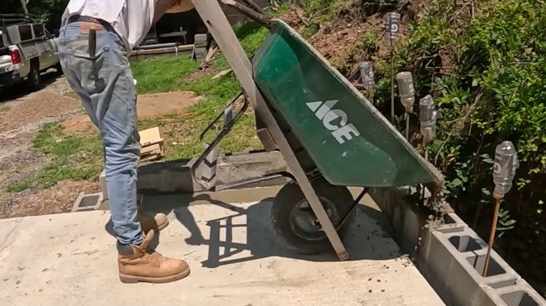 Person filling cinder blocks with wet concrete