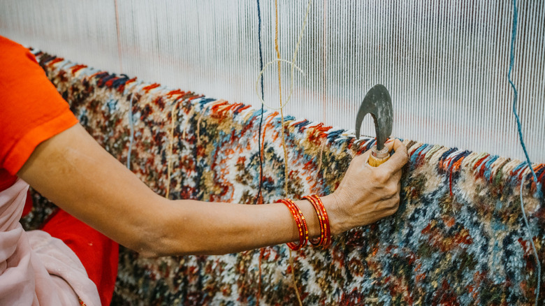 Person at a loom handcrafting a custom rug