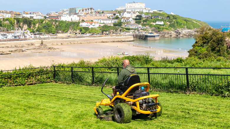 Person sitting on a riding lawn mower inside a fence