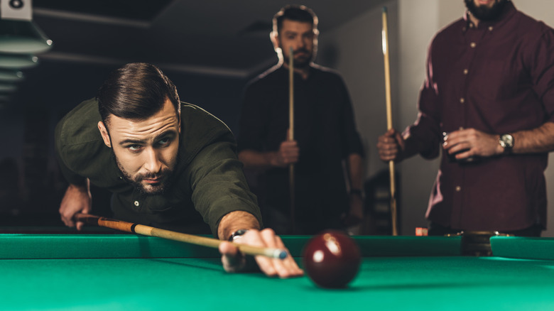 three men playing pool on pool table