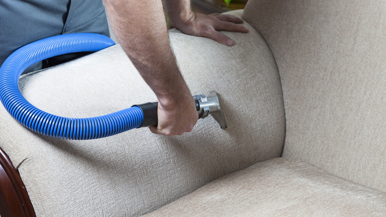 man steam cleaning a couch