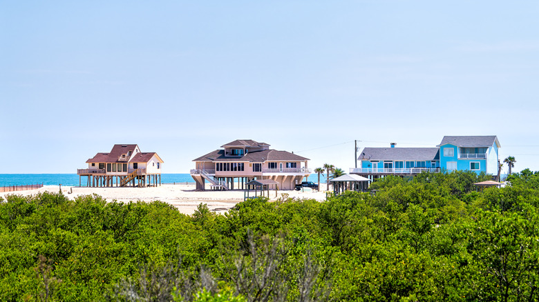 Three houses on stilts on the beach overlooking the ocean