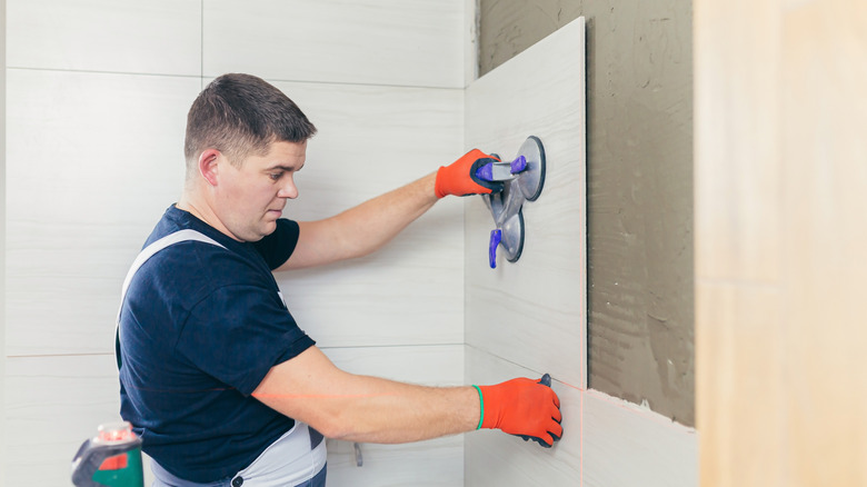 Professional worker laying bathroom tiles