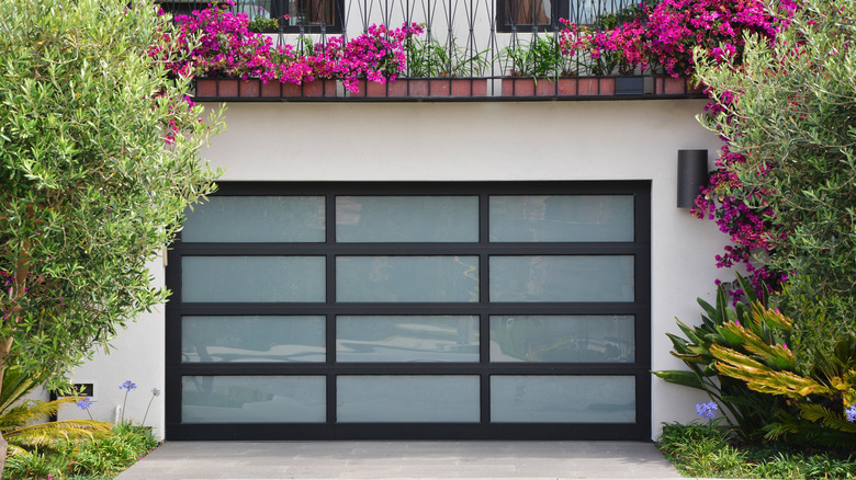 Glass garage door surrounded by lush plants