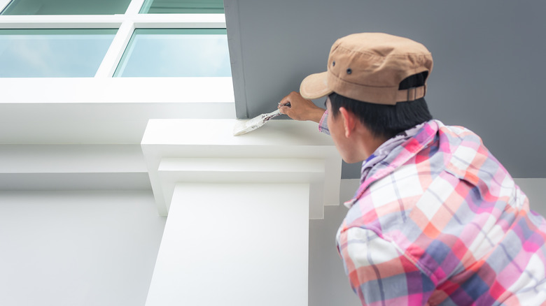 Man painting trim on a house