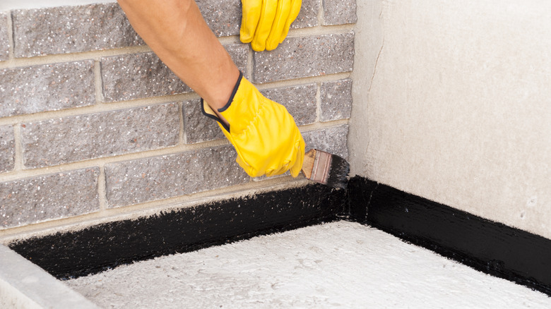 worker applying bitumen to waterproof