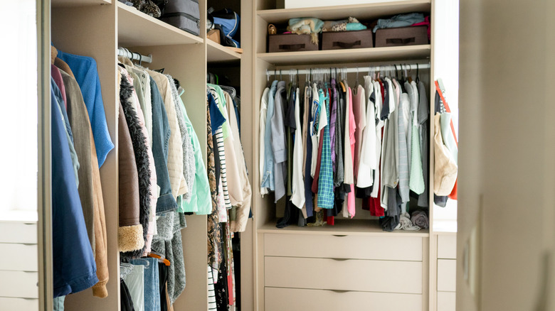 A very full and nicely organized walk-in closet full of clothes.