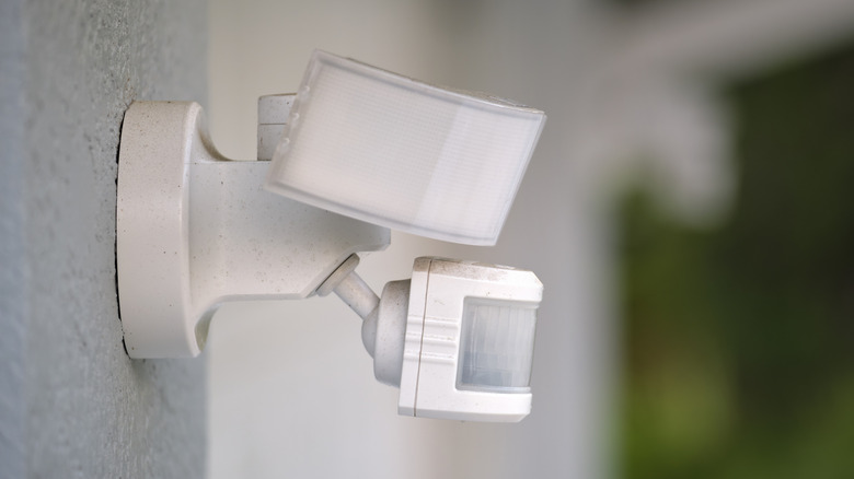 A white motion sensor light mounted on an exterior wall of a house