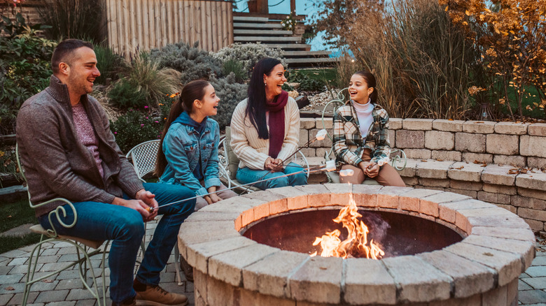 A family sat around a fire pit roasting marshmallows