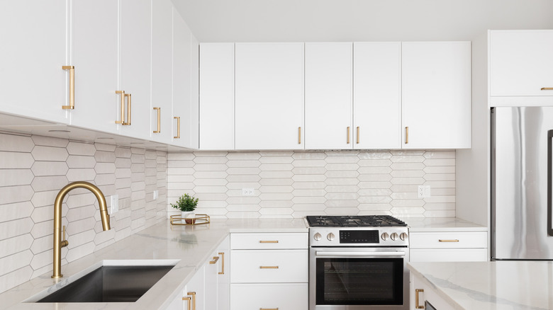 White backsplash in an all-white kitchen, below overhead cabinets
