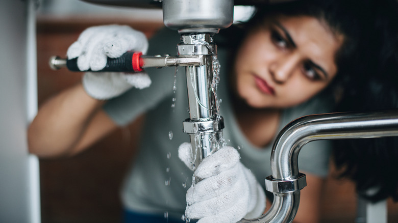 Person fixing leaking sink pipe