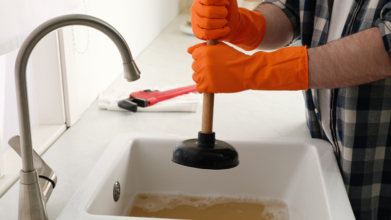 Plumber clearing clogged drain