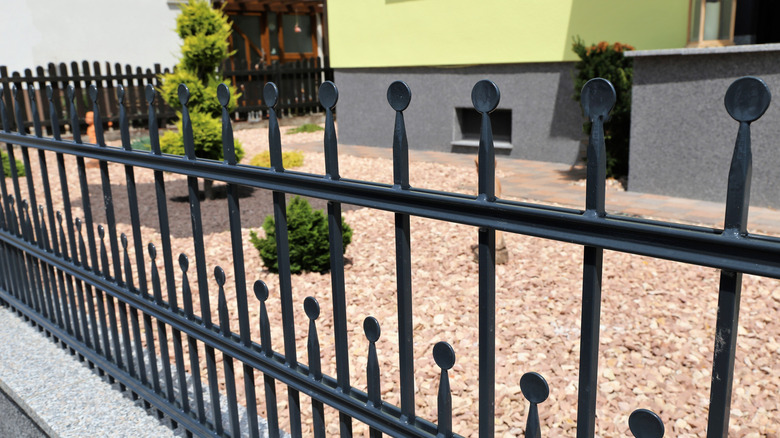 A black aluminum garden fence with circular fencepost tips
