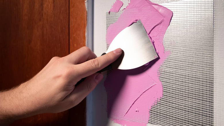 Person patching and mudding drywall