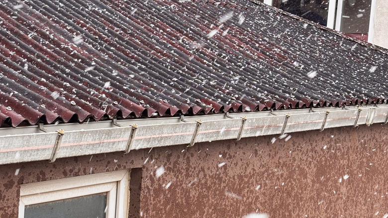 Snow falling on the roof of a house