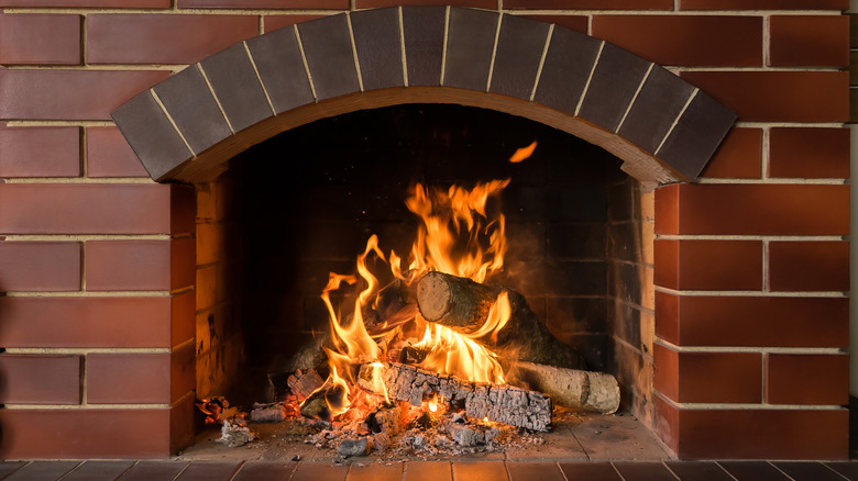 Red brick fireplace burning logs
