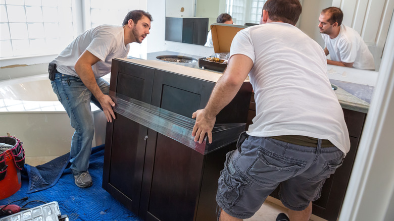 two men installing bathroom cabinets