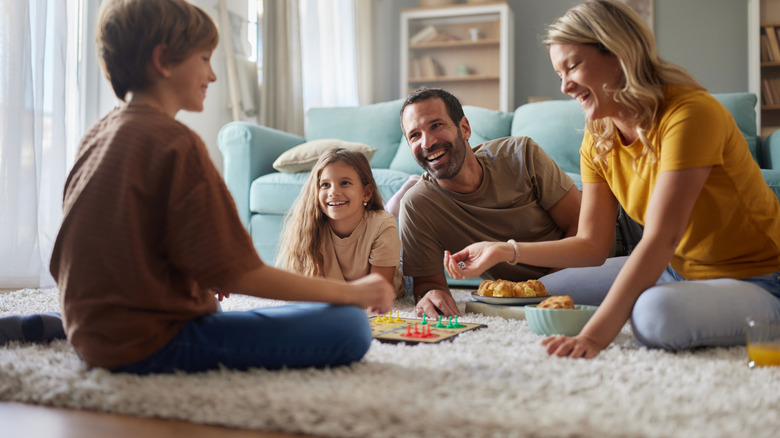 A family is sitting and laid out on a carpet while playing a board game