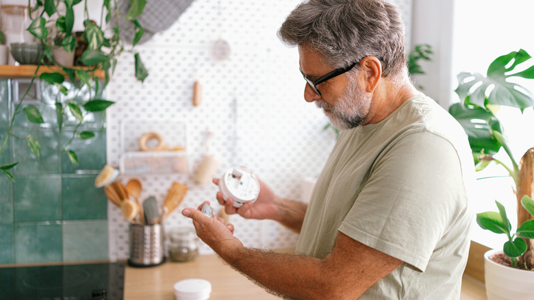 A man looking at the battery in a smoke detector