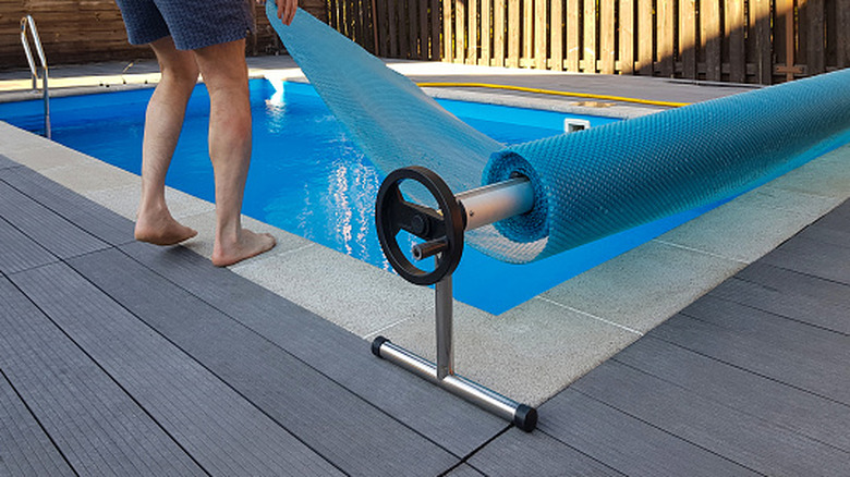A man adding a cover over a pool