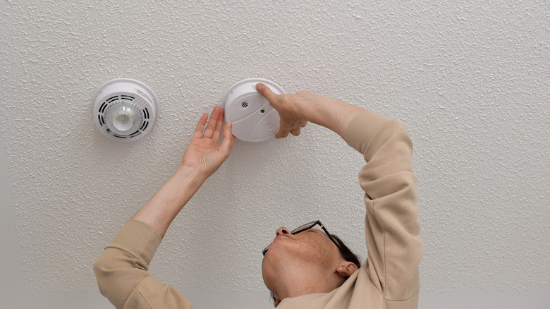 Woman checking smoke detector