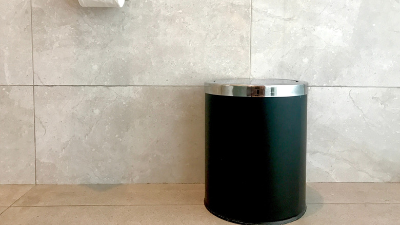 A black trash can with a silver top in a bathroom
