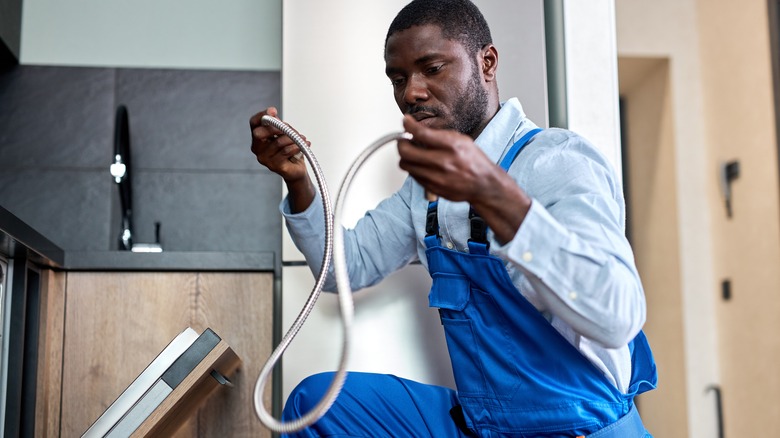 man holding dishwasher hose