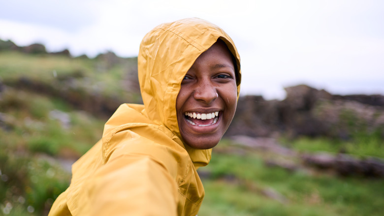 Young woman laughing, wearing a yellow rain jacket