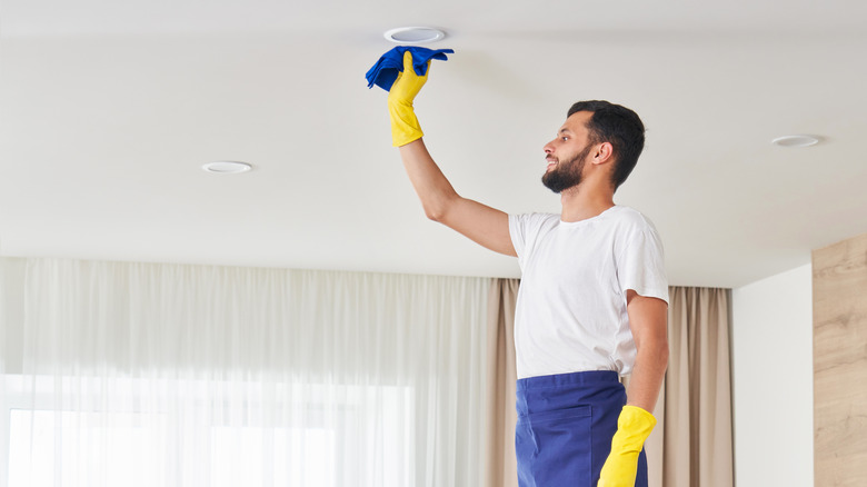 Man cleaning ceiling with cloth