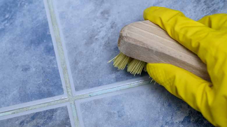Gloved hand scrubbing tile grout