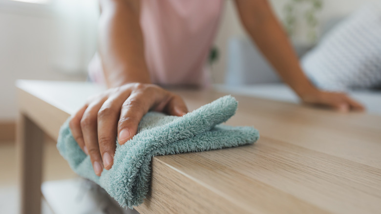 A hand dusting furniture