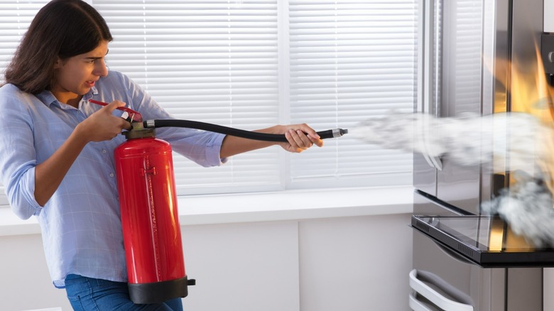 Woman spraying fire extinguisher into oven fire