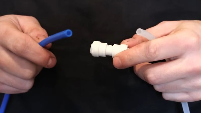 Person inspecting a plastic water supply line for a fridge