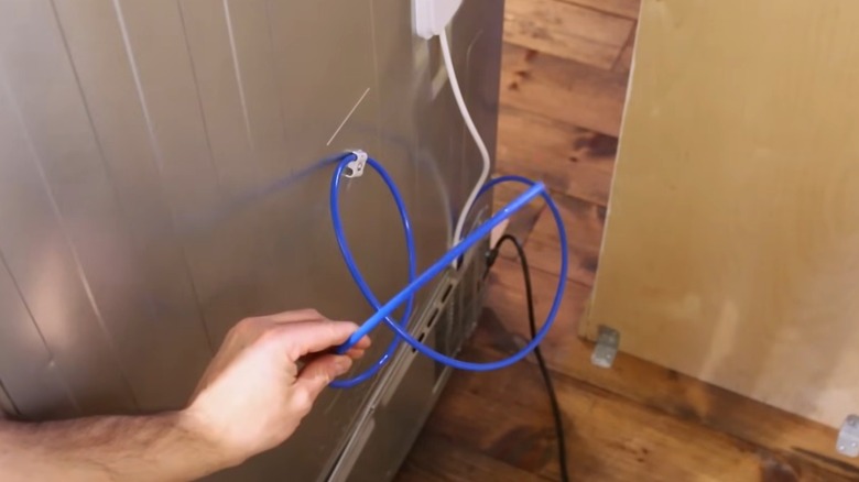 Person inspecting a refrigerator water line