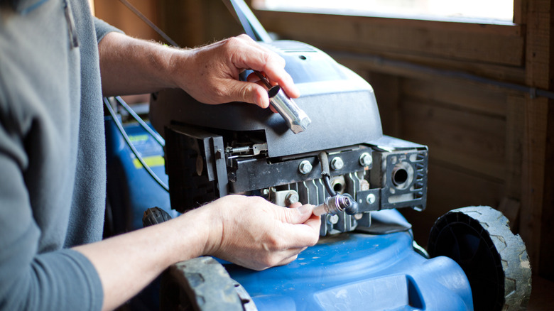 Person inspecting a lawn mower's spark plug