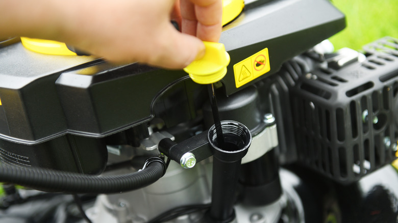 Person checks oil levels on lawn mower