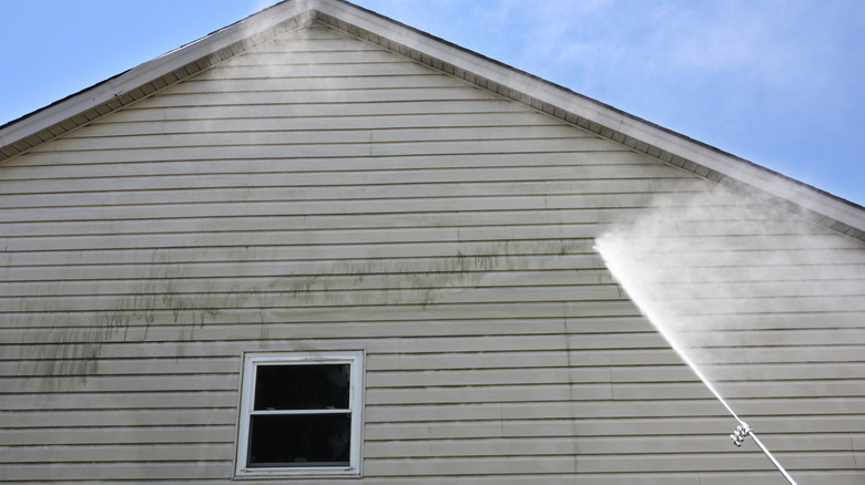 Dirty siding being pressure washed