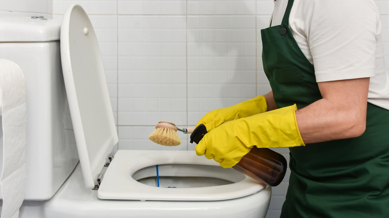 Man in yellow rubber gloves cleaning toilet