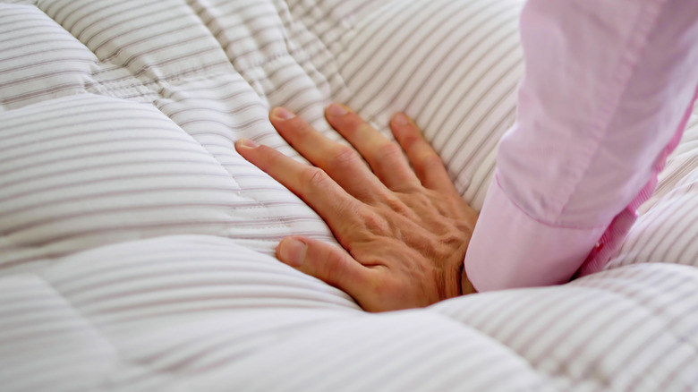 Woman's hand testing a memory foam mattress topper