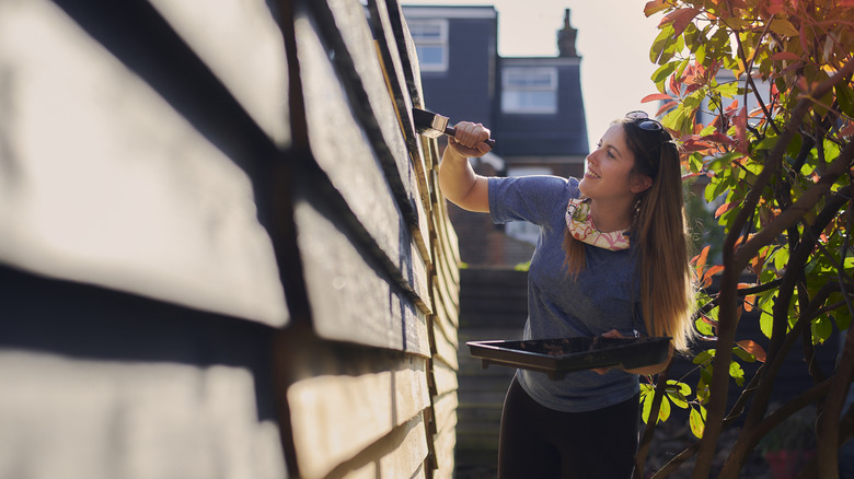 A person painting a fence in the backyard