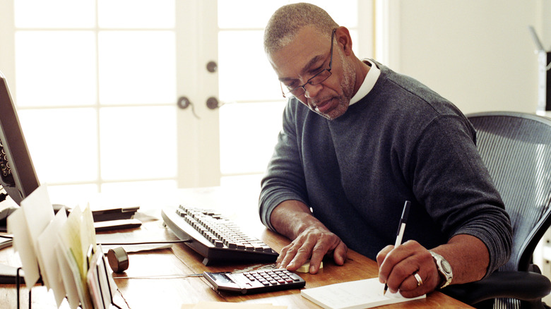 Man writing at computer desk