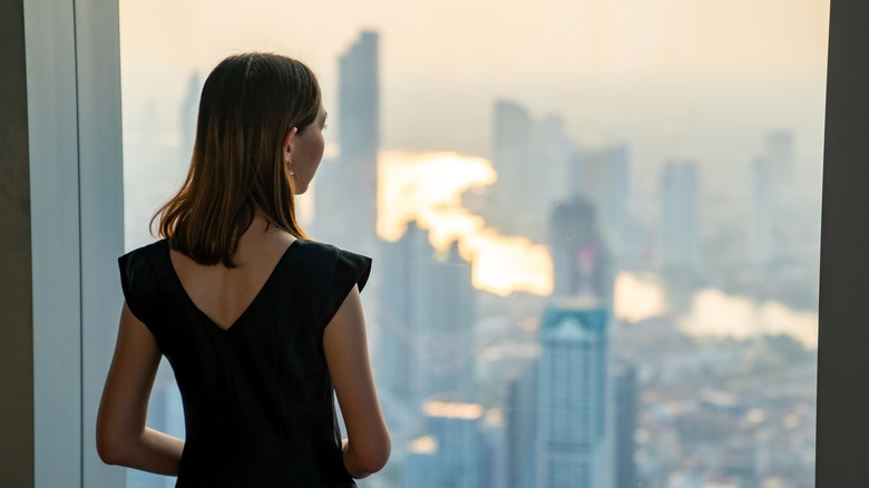 Woman looking out city window