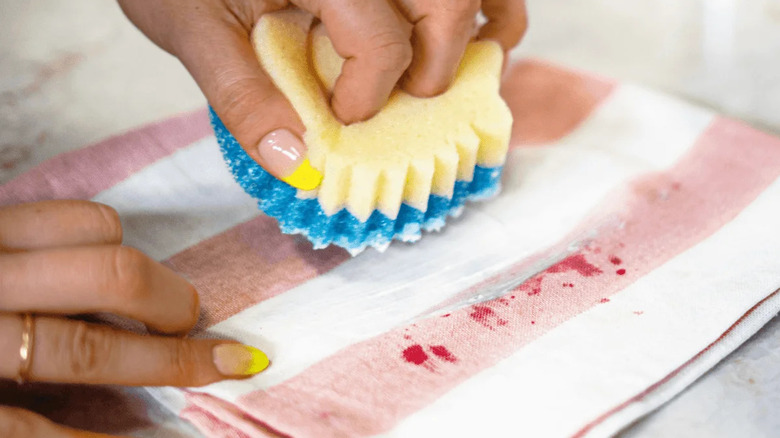 person cleaning stain on towel