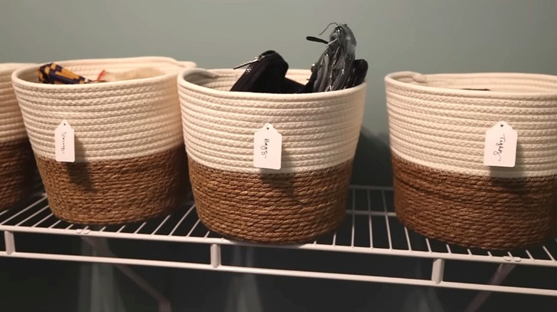 Woven baskets with Dollar Tree labels sitting on a wire closet shelf