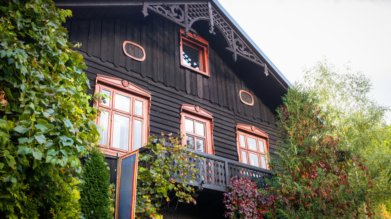 A home with a black exterior with trees on either side