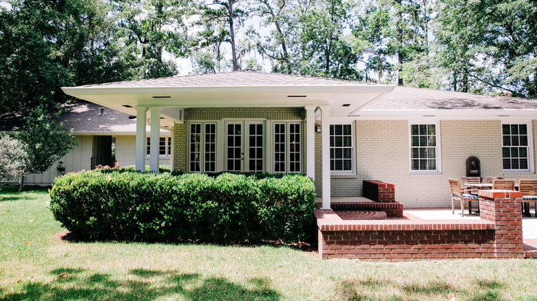 Back yard of a midcentury modern home with shrubs and manicured lawn